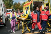 Nach einem Massenunfall werden mehrere Patienten am Johannes-Thal-Klinikum eingeliefert. Emma Jahn (Elias Agbaglah, l.) und Mikko Rantala (Luan Gummich, 3.v.r. mit Komparsen) k&uuml;mmern sich um Frieda Kantak (Pauline R&eacute;nevier, M.).