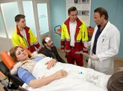 Nadine Dressler (Angeline Anett Heilfort, liegend) hat sich bei einer Auseinandersetzung mit Florian K&ouml;hler (Martin Ontrop, 2. v. li.) den Oberarm verletzt. Die beiden werden von Sanit&auml;ter (Komparse, li.) und Notarzt (Markus Neumann, 2. v. re.) in die Sachsenklinik gebracht. Nadine Dressler ist auf den Jugendamtsmitarbeiter losgegangen, weil dieser ihr ihre Tochter Dunja entziehen wollte. Nachbarn hatten das Jugendamt verst&auml;ndigt, da sie Kinderschreie aus der Wohnung der Frau geh&ouml;rt hatten. K&ouml;hler ist mit einer Platzwunde am Kopf davon gekommen. Nadine Dressler hingegen muss von Dr. Martin Stein (Bernhard Bettermann, re.) n&auml;her untersucht werden.