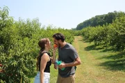 Kara Rojer and Guillermo Rojer biting a peach at a farm in Virginia