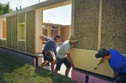 Hausbau mit Strohballen: Die Zimmerer der Zimmerei Tjhen bringen die Holzfaserplatten auf die Außenwand. Hausbau mit Strohballen: Die Zimmerer der Zimmerei Tjhen bringen die Holzfaserplatten auf die Außenwand.