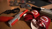 Retro-Videospiele, eine Plastikpistole und Essensverpackungen liegen auf einem Tisch.