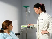 Rebecca (Alma Leiberg, links) l&auml;sst sich unter fadenscheinigen Sorgen um ihre Gesundheit von Dr. Eichhorn (Cheryl Shepard) den Perfusor erkl&auml;ren.