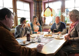 Der Pflegepr&uuml;fer (Wolfgang Haas, links) ist zu Besuch und befragt Johanna (Saskia Vester, rechts), Heinz (Heinz-Josef Braun, 2. von rechts) und deren Kinder Caroline (Fanny Krausz) und Christof (Franz-Xaver Br&uuml;ckner) zu Oma Magdalenas Zustand.