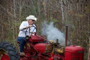Marty Raney driving a red tractor. Smoke flows out of the side.