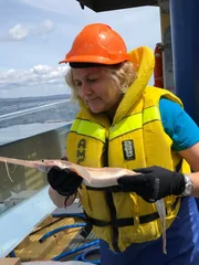 Jane Williamson holds a sawshark and looks at it while standing next to the tank.