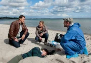 Am Strand von Travem&uuml;nde wurde die Leiche von Bj&ouml;rn Aufderheide gefunden. Er hat das Wochenende mit seinem Kegelclub im Hotel Strandidylle verbracht. V.l.n.r. Finn Kiesewetter (Sven Martinek), Sandra Schwartenbeck (Marie-Luise Schramm) und Pathologe Dr. Strahl (Christoph Tomanek), Bj&ouml;rn Aufderheide (Leiche: Komparse)