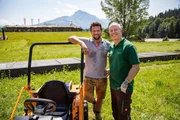 Amazing Hotels &ndash; Biohotel Stanglwirt, &Ouml;sterreich Besitzer Johannes Hauser und Moderator Rob Rinder neben einem Rasenm&auml;her vor dem Stanglwirt Hotel in &Ouml;sterreich