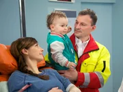 Sabine Schrader (Anne Werner, li.) wird nach einem Sturz von einer Leiter in die Sachsenklinik eingeliefert. Ihren kleinen Sohn Tim (Finn Graul, mi.) musste der Notarzt (Komparse, re.) mitnehmen, da Sabine alleinerziehend ist. Sabine Schrader (Anne Werner, li.) wird nach einem Sturz von einer Leiter in die Sachsenklinik eingeliefert. Ihren kleinen Sohn Tim (Finn Graul, mi.) musste der Notarzt (Komparse, re.) mitnehmen, da Sabine alleinerziehend ist.