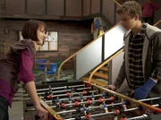 Coco (Luisa Liebtrau) und Tamas (Edzard Ehrle) spielen eine Partie Tischkicker gegeneinander.