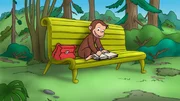 Curious George sitting on a bench.