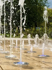 Many small splashing dancing fountains in summer Warsaw park