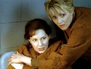Brenna (Alison Matthews, li.) wurde von Administrator Caulder angeschossen, als sie SG-1 nach Hause schicken wollte. Thera (Amanda Tapping), oder jetzt wieder Carter, versucht ihr zu helfen.