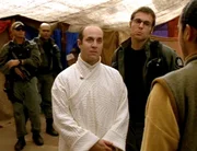 Jackson (Michael Shanks, 2ter re.) &cedil;berredet Lotan (Brian Markinson, mi.) mit ihm die Enkaraner zu besuchen. Er stellt ihm Eliam (Alessandro Juliani, re.) vor. Er hofft so das Gewissen von Lotan beeiflussen zu k^nnen. Colonel O'Neill (Richard Dean Anderson, li.) und Teal'c (Christopher Judge) beobachten diese Action skeptisch... Das SG-1-Team steht zwischen zwei extraterrestrischen Zivilisationen, die den selben Planeten kolonisieren wollen. Doch die Ansiedlung der einen bedeutet die sichere Ausrottung der anderen Zivilisation ...