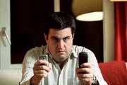 Bastian (Bastian Pastewka) telefoniert ununterbrochen, gern auch von zwei Handys gleichzeitig. Er will unbedingt den Journalistentarif f&uuml;r sein Handy haben. Im Moment h&auml;ngt er allerdings in der Warteschleife der Hotline ...