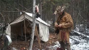 Oliver tying his coat, standing outside wall tent.