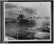 Pearl Harbor, Hawaii - The U.S.S. Neosho, navy oil tanker, cautiously backs away from her berth (right center) in a successful effort to escape the Japanese attack on Pearl Harbor. At left the battleship USS California lists after aerial blows. Other crippled warships and part of the hull of the capsized USS Oklahoma may be seen in the background. The Neosho was later sunk in the Coal sea.