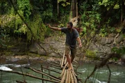 Hazen schreitet vorsichtig &uuml;ber eine prek&auml;re Bambusbr&uuml;cke &uuml;ber einen schnell flie&szlig;enden Fluss mitten im Dschungel.