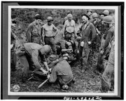 Guadalcanal - A casualty from the front line fighting is being transferred from the makeshift stretcher before being taken through jungle and down river to near hospital.