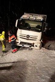 Odda, Norway - Thord Paulsen and Erlend Turtveit secure wires on a truck in snowy conditions.