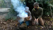 Matt Graham and Joe Teti making a fire, smoke starting.