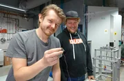 Das Erfinder-Duo Dimitri Benke (links) und Dr. Maximilian Fries aus Darmstadt. Benke h&auml;lt ihre Erfindung, das magnetischen K&auml;ltemittel, in den Fingern.