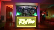 The LED lighting of the 1300 liter fish tank, in which a colorful crowd of underwater inhabitants cavort, flashes to the beat of the music that "Redfoo" plays at the DJ station.