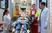 Dr. Philipp Brentano (Thomas Koch, re.) und Oberschwester Arzu Ritter (Arzu Bazman, li.) nehmen &uuml;berrascht Schwester Ingrid (Jutta Kammann, 2.v.li.) mit der autistischen Luna (Emma Br&uuml;ggler, liegend) in der Sachsenklinik auf. Notarzt Dr. Daniel Lorenz (Markus Neumann, 2.v.re.) vermutet ein Sch&auml;del-Hirn-Trauma und ein Thorax-Trauma.