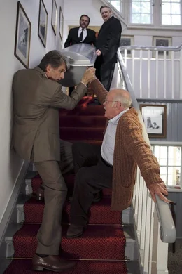 Gemeinsam mit den Sargtr&auml;gern (oben) des Bestattungsinstitutes tragen Hubert (Joost Siedhoff, r.) und Stefan (Walter Sittler, l.) den geschlossenen Sarg die Treppe hinunter. Hubert ist sichtlich &uuml;berfordert und st&uuml;rzt, der strafende Blick trifft nat&uuml;rlich Sohn Stefan ...