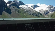 Blick auf eine Staumauer vor einem Bergsee, umgeben von hohen schneebedeckten Gipfeln. Blick auf eine Staumauer vor einem Bergsee, umgeben von hohen schneebedeckten Gipfeln.