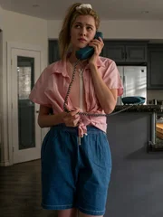 Janelle Kirby on the phone in kitchen with her boyfriend Mike in the background.