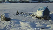 Pike Mike stands near his barge along a wall of ice.