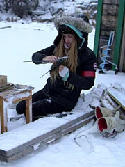 Molly kneel in the snow near a table at Molly's barge.