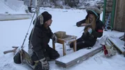 Stephen and Molly kneel in the snow near a table at Molly's barge. Stephen and Molly kneel in the snow near a table at Molly's barge.