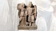 Die Statuette wurde 1903 bei Grabungen in Carnuntum entdeckt. Sie zeigt die r&ouml;mische Kriegs-G&ouml;ttin &bdquo;Minerva&ldquo; und &bdquo;Genius Immunium&ldquo; den Schutzgeist der Soldaten. Heute ist die Statuette farblos und blass - welche Farben hatte sie einst?