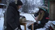 Stephen and Molly kneel in the snow near a table at Molly's barge.