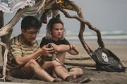 Caleb (Joshua Tan, l.) hat eine alte vergrabene Schiffsglocke am Strand entdeckt, nachdem er Issie (Macey Chipping, r.) offenbart hat, dass er homosexuell ist.