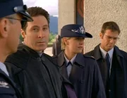 Omoc ist gestorben. SG-1 (Richard Dean Anderson, li. als O&acute;Neill, Amanda Tapping als Carter, Michael Shanks als Daniel) ist zum Begr&auml;bnis nach Tollana gereist, dort treffen sie Narim (Garwin Sanford, 2ter li.)...