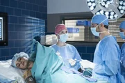 Zoe (Melina Fabian, l.) hat sich eine Sehne an der Schulter gerissen. Julia Berger (Mirka Pigulla) und Dr. Niklas Ahrend (Roy Peter Link, r., mit Komparsin) m&uuml;ssen operieren.