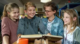 Mia, Benny und Alice zeigen Johannes (2.v.l.) im HQ das legend&auml;re Pfefferk&ouml;rner-Buch.
