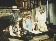 Laura (Melissa Gilbert, l.), Charles (Michael Landon, 2.v.l.), Mary (Melissa Sue Anderson, M.) und Caroline (Karen Grassle) bestaunen ein Musikinstrument.