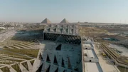 Blick von oben auf das Grand Egyptian Museum mit den Pyramiden im Hintergrund.