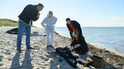 Am Strand von Wismar wird die Leiche des Kitesurfers Henning Waslund (Adrian Otzdorff, M.) angesp&uuml;lt. Die Abwehrverletzungen an seinem K&ouml;rper lassen f&uuml;r Dr. Helene Sturbeck (Katharina Blaschke, r.) keinen Zweifel: Ein Unfall kann ausgeschlossen werden. Kriminaltechnikerin Roswitha Prinzler (Silke Matthias, 2.v.l.) gibt Lars P&ouml;hlmann (Dominic Boeer, l.) und Karoline Joost (Nike Fuhrmann, 2.v.r.) erste Informationen zum Fall.