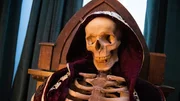 A close up of the skeleton earing a purple cloak