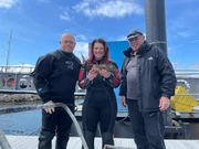 Ross Kemp (links), der Meeresarch&auml;ologe Mallory Haas und der Tauchleiter (rechts) Neil Brock halten die kupferne Rumpfscheide in der Hand, die sie am Standort des Kriegsschiffs HMS Amethyst von 1799 geborgen haben. Plymout