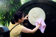 Con Dao, Ba Ria-Vung Tau Province, Vietnam: A devotee wipes a plaque of Vo Thi Sau's face at the cemetery. She is regarded as a national martyr for her patriotic actions during the French Regime.