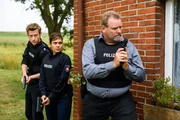 Kriminalhauptkommissar Brockhorst (Felix V&ouml;rtler, r.) n&auml;hert sich mit gezogener Waffe dem Haus des Tatverd&auml;chtigen. S&uuml;her &Ouml;zl&uuml;g&uuml;l (Sophie Dal, M.) und Henk Cassens (Maxim Mehmet, l.) geben ihm Deckung.
