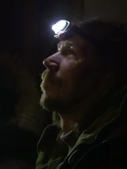 Stephen and Allyce stand in the dark with head strap flashlights and search for a missing dog.