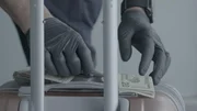 Ein CBP-Beamter zählt das Bargeld eines Passagiers und benutzt das Gepäck des Passagiers als flache Unterlage zum Zählen. (National Geographic) Ein CBP-Beamter zählt das Bargeld eines Passagiers und benutzt das Gepäck des Passagiers als flache Unterlage zum Zählen. (National Geographic)