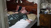 Medium Wide Shot: SIGMUND WERNER lies in bed with his eyes closed, looking ill.