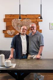 Von links: Bernhard Sitter und Ewald Sitter, Sharepic, Arm in Arm in die Kamera schauend.